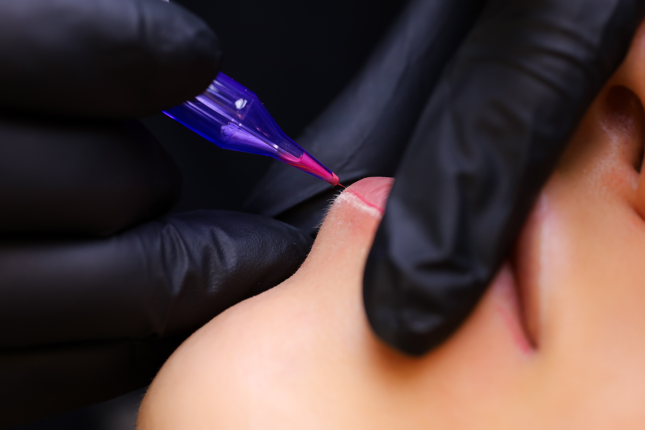 A Tattoo Artist in Black Gloves Holds a Tattoo Machine, and the